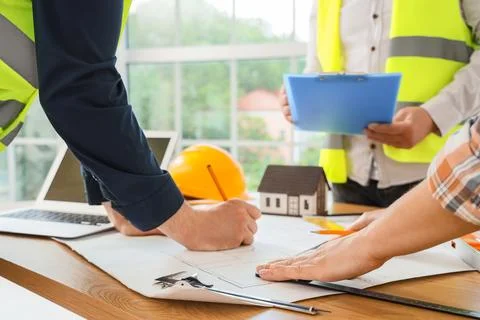 Construction workers planning building project with blueprints Stock Photos