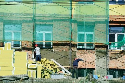 Construction workers plaster the facade of the building. Restoration of the h Stock Photos