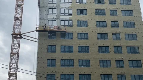 Construction workers on platform building high-rise structure with crane in.. Stock Footage 344456471