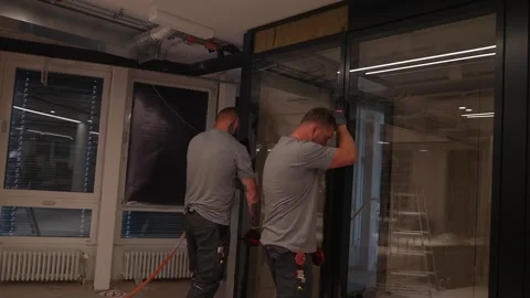 Construction workers position and secure a large glass partition inside a Stock Footage 331304604