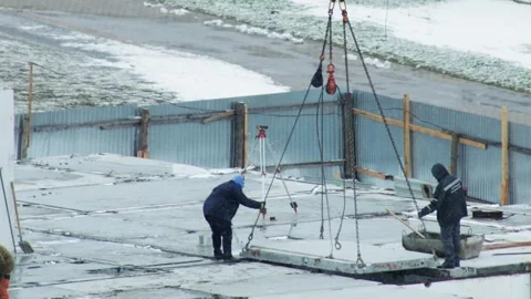Construction workers positioning concrete slab using crane on building site. Man Stock Footage 344864497