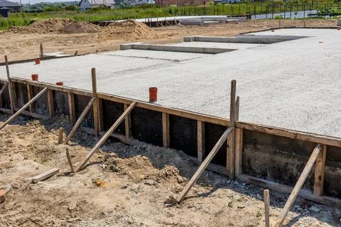 Construction workers pour cement to create a solid foundation for new house.. Stock Photos