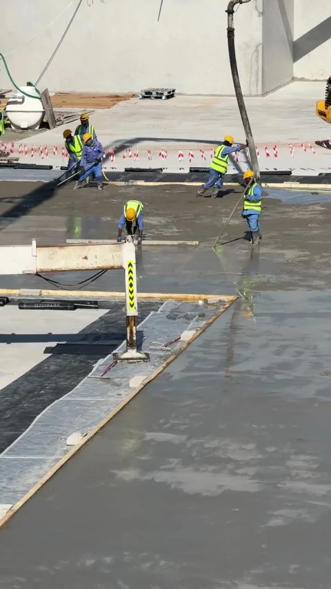 Construction workers pour concrete flooring at a large building site, shaping Stock Footage 304813969