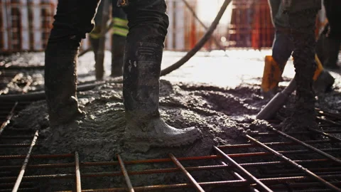 Construction workers pour concrete onto rebar foundation at sunset. Stock Footage 329611291