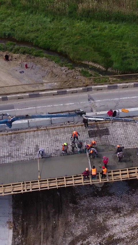 Construction workers pouring concrete on a bridge renovation project, showcasing Stock Footage 313927381