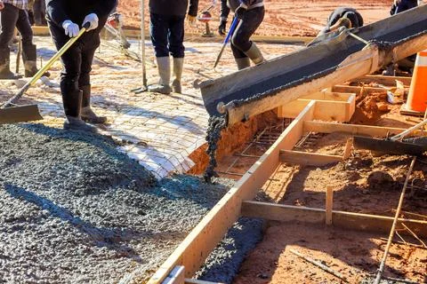 Construction workers pouring concrete at building site in bright daylight during Foto stock