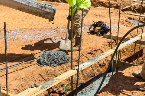 Construction workers pouring concrete digging at building site during works day Stock Photos