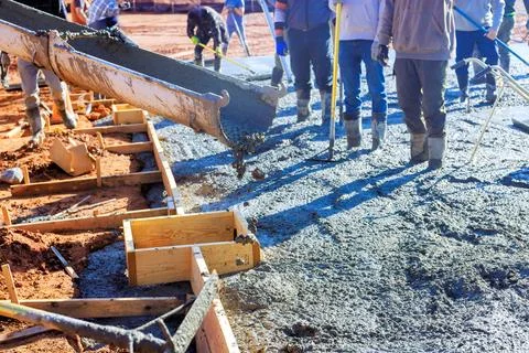 Construction workers pouring concrete for foundation on works day at building Stockfoto's
