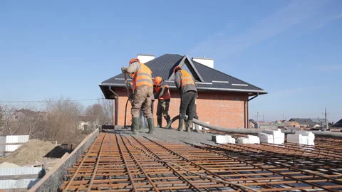 Construction workers pouring concrete on a rooftop under clear blue sky, safety Stock Footage 309206020