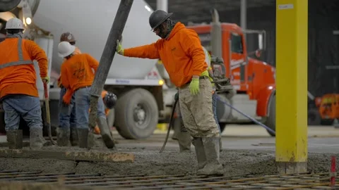 Construction workers pouring a concrete slab with rebar from a mixer. Stock Footage 257394913