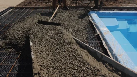 Construction workers pouring liquid concrete for swimming pool patio area i.. Stock Footage 334934406