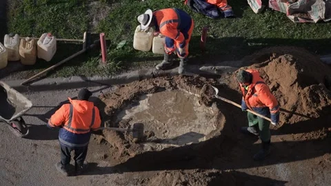 Construction workers pouring water into a hole in the ground Видео 308918049