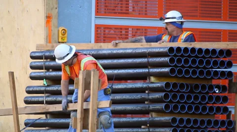 Construction workers prepare pile of pipes at development site Video stock 34129999
