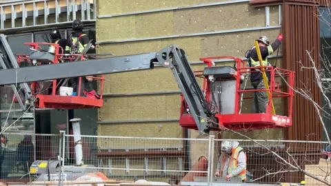 Construction workers on red boom lifts installing insulation and exterior siding Stock Footage 334172356
