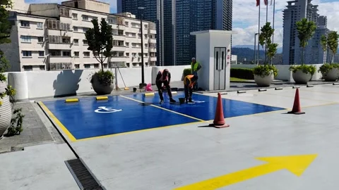 Construction workers refresh a disabled parking bay with weather-resistant Stock Footage 308453254