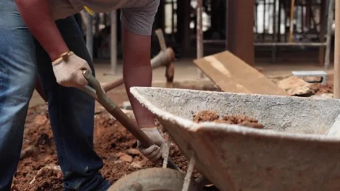Construction workers removing soil and debris with a shove and a pushcart Stock Footage 255684430