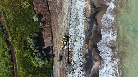 Construction workers repair a shoreline and build a barrier at a beach during Video stock 337910907