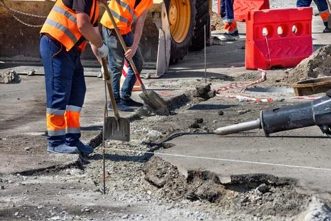 Construction workers repairing pavement in a busy urban area during dayligh.. Stock Photos