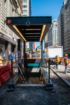 Construction workers replacing the sidewalk around the entrance to the F trai Stock Photos