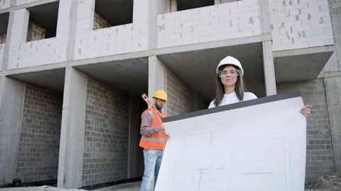 Construction workers review building plans in slow motion at a construction site Stock Footage 303228070