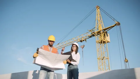 Construction workers reviewing blueprints in slow motion with a crane Stock Footage 303228311