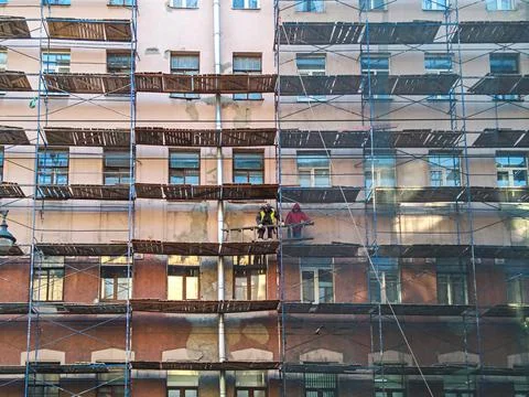 Construction workers on the scaffold around old renovating building Stock Photos
