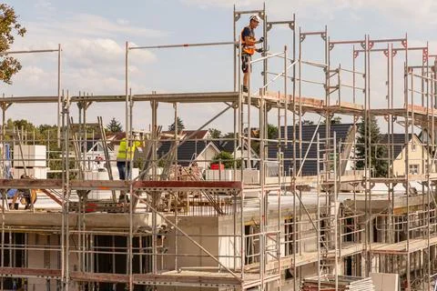 Construction workers on scaffolding at building site with blue sky Stockfoto's