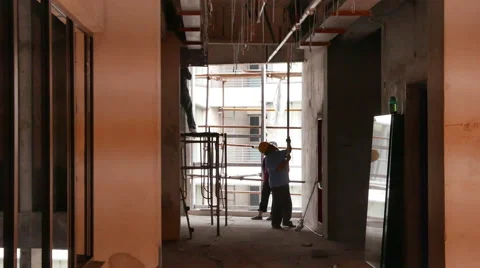 Construction Workers Screwing In Supports as Welding Flashes In Foreground - 4K Stock Footage 51259688