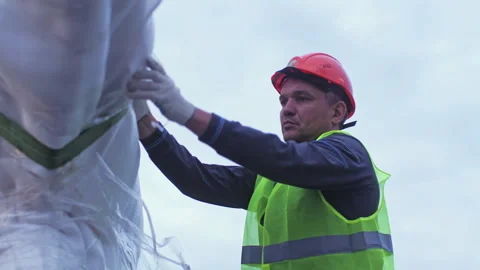 Construction workers secure packaged star onto crane using cords Vídeo Stock 258468990