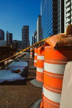 Construction workers set up safety barriers on the street. City buildings ris Stock Photos