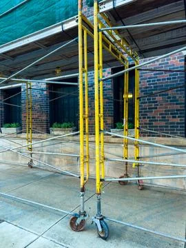 Construction workers set up scaffolding around a building for repair work in  Stock-Fotos