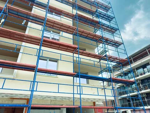 Construction workers set up scaffolding on a building during daylight to pr.. Stock Photos