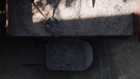 Construction workers shovel crushed stone from a dump truck into a wheelbarrow Video stock 341470111