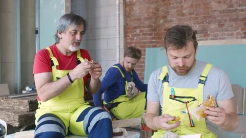 Construction workers sitting on work site and having meal Stock Footage 133640578