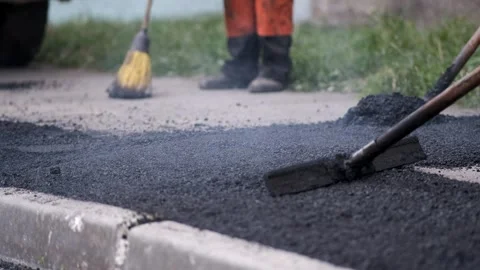 Construction workers spreading and leveling hot steaming asphalt with hand .. Stock-Footage 339801959