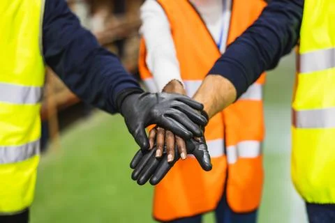 Construction workers stacking hands showing teamwork and unity Stock Photos