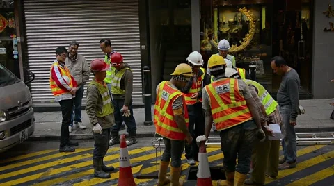 Construction workers stand around an open man hole in urban Hong Kong Vidéo 67138907
