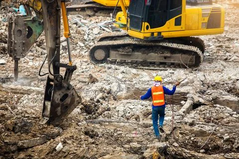 Construction workers standing among the rubble of demolished buildings with w Stock Photos