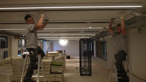Construction workers standing on ladders carefully detach a suspended ceiling Stock Footage 331304684