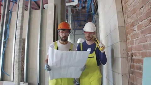 Construction workers study architectural blueprint on work site Stock Footage 133637177