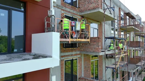 Construction workers on suspended platform installing facade panels, New Stock Footage 311076346