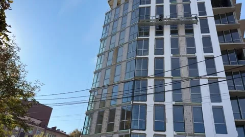 Construction workers on a suspended platform installing windows Stock Footage 320267318