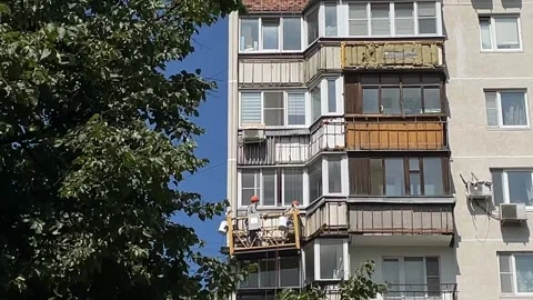 Construction workers on a suspended platform repairing an apartment buildin.. Stock Footage 342345005