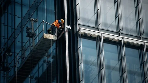 Construction workers on a suspended platform on a skyscraper glass facade 動画素材 93180229