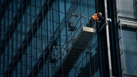 Construction workers on a suspended platform on a skyscraper glass facade 動画素材 93180243