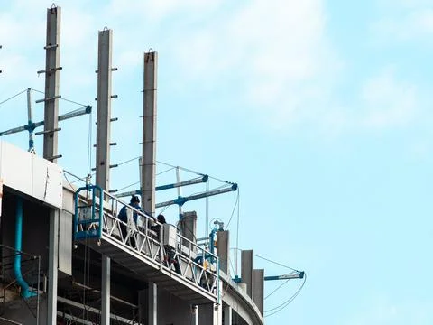 Construction workers on suspended working platform gondola at rooftop of cu.. Stock Photos