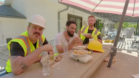 Construction Workers Taking a WellDeserved Lunch Break Enjoying Their Meal Under Stock Footage 306279263