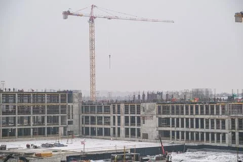 Construction workers on top of new building in progress, with a large crane Stock Photos