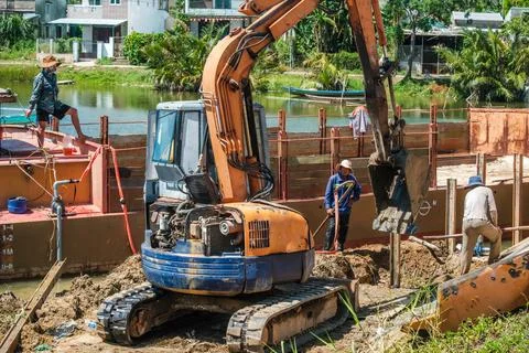 Construction workers with a tracked excavator building an irrigation channe.. Stock-Fotos