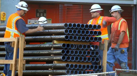 Construction workers unload pipes at new development site Stock Footage 34134466
